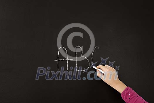 Hand writing on blackboard with piece of chalk