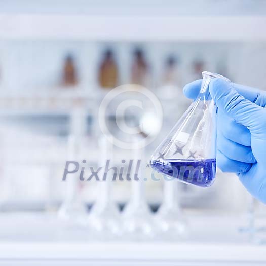Hand holding a measuring glass with blue fluid Hand holding a measuring glass with blue fluid