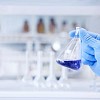 Hand holding a measuring glass with blue fluid