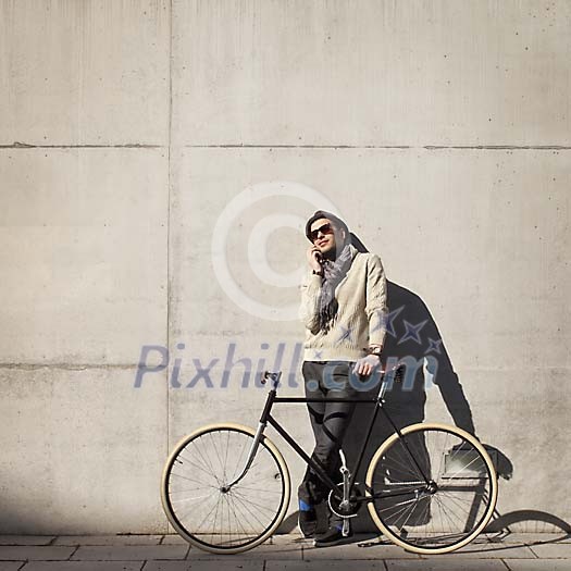 Hipster man with a bike by the wall Hipster man with a bike by the wall