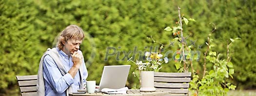 Man sitting in the garden with laptop Man sitting in the garden with laptop