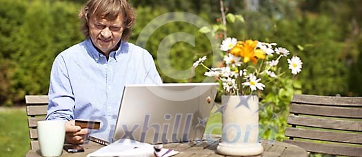 Man doing online shopping in the garden Man doing online shopping in the garden