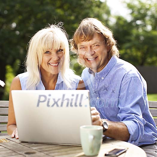 Couple sitting in the garden with laptop Couple sitting in the garden with laptop