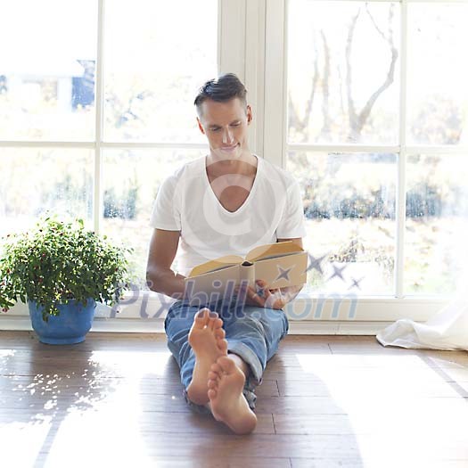 Man sitting by the window, reading a book Man sitting by the window, reading a book