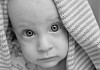 Big-eyed baby looking under the towel