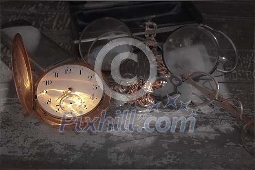 Golden pocket watch with dusty eyeglasses Golden pocket watch with dusty eyeglasses
