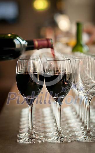 Red wine being poured to the glasses Red wine being poured to the glasses