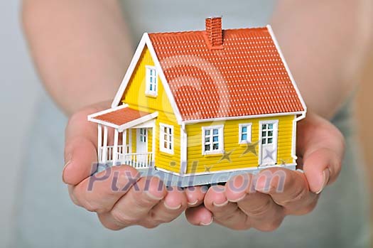 Human hands holding a toy house Human hands holding a toy house