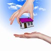 Human hand against blue sky background and house