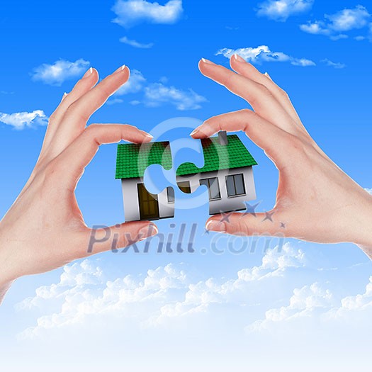 Human hand against blue sky background and house