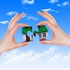 Human hand against blue sky background and house