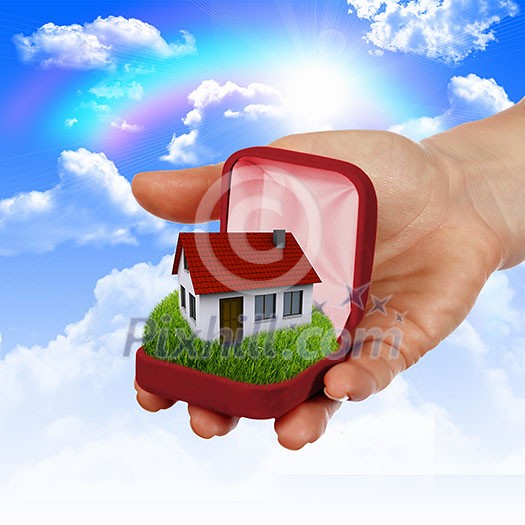 Human hand against blue sky background and house Human hand against blue sky background and house