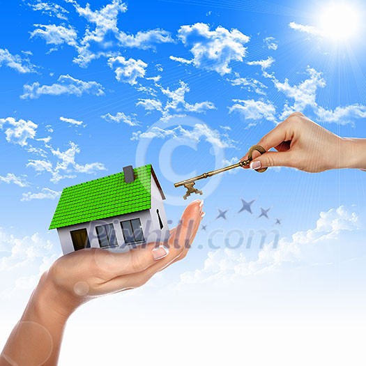 Human hand against blue sky background and house Human hand against blue sky background and house