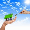 Human hand against blue sky background and house