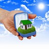 Human hand against blue sky background and house