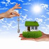 Human hand against blue sky background and house