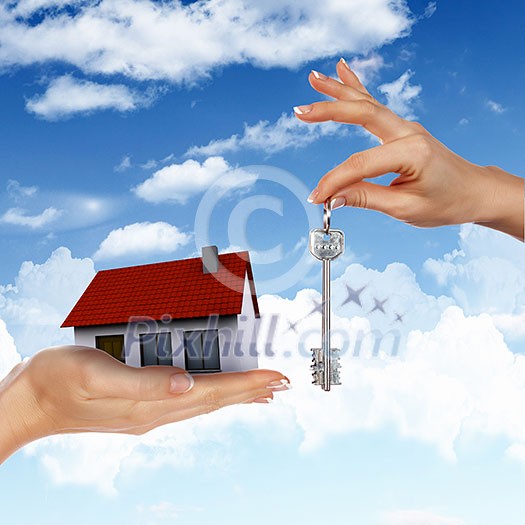 Human hand against blue sky background and house Human hand against blue sky background and house