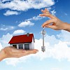 Human hand against blue sky background and house