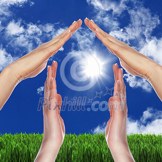 Human hand against blue sky background and house Human hand against blue sky background and house