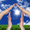 Human hand against blue sky background and house