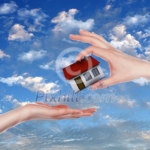 Human hand against blue sky background and house Human hand against blue sky background and house