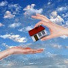 Human hand against blue sky background and house