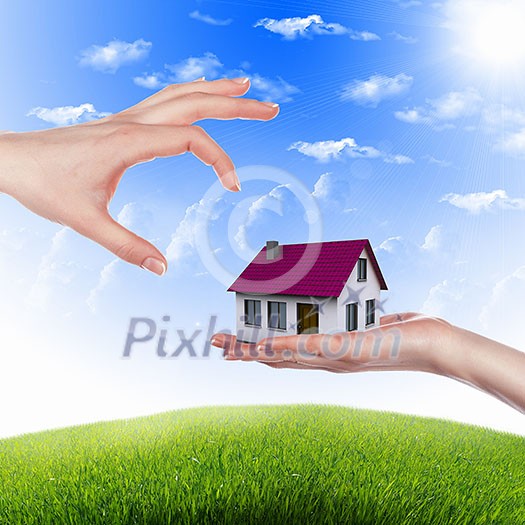 Human hand against blue sky background and house Human hand against blue sky background and house