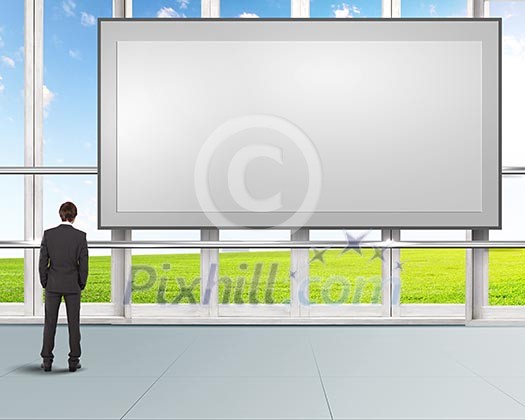 Business person standing near a blank billboard Business person standing near a blank billboard