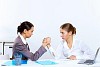 Two young women in business wear arm wrestling in office