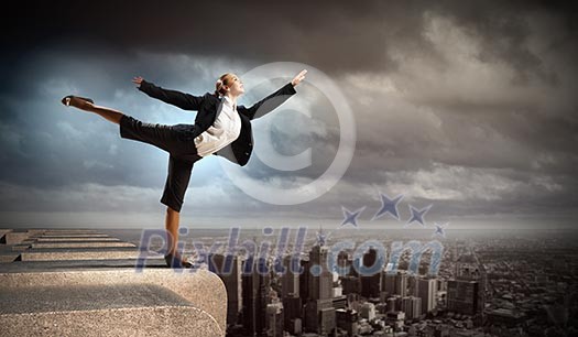 Image of pretty businesswoman balancing on the roof above cityscape Image of pretty businesswoman balancing on the roof above cityscape