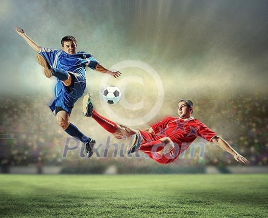 two football players in jump to strike the ball at the stadium