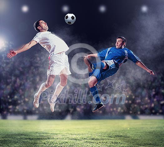 two football players in jump to strike the ball at the stadium two football players in jump to strike the ball at the stadium