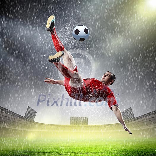 football player in red shirt striking the ball at the stadium under rain football player in red shirt striking the ball at the stadium under rain