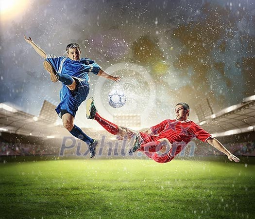 Two football players in jump to strike the ball at the stadium Two football players in jump to strike the ball at the stadium