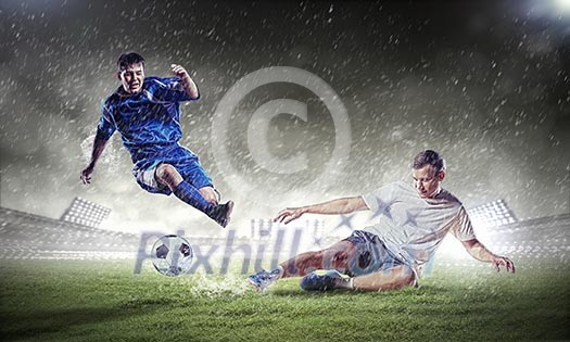 Two football players in jump to strike the ball at the stadium Two football players in jump to strike the ball at the stadium