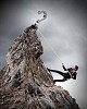 Businessman climbing mountain with question sigh on top