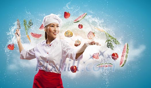 Asian female cook with knife cutting fruits and vegetables in air Asian female cook with knife cutting fruits and vegetables in air