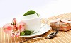 White cup with pink flowers and small gifts on a light table.