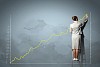 businesswoman standing on ladder drawing diagrams and graphs on wall