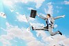 Image of a businessman jumping high against blue sky background