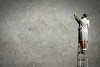 Businesswoman standing on ladder drawing diagrams and graphs on wall