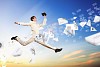 Image of a businessman jumping high against blue sky background