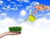 Hand with a small watering can watering green grass
