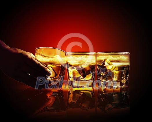 Hand holding one of three glasses of whiskey with ice and sky illustration in Hand holding one of three glasses of whiskey with ice and sky illustration in