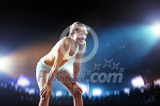 Fitness woman standing against stadium lights background Fitness woman standing against stadium lights background