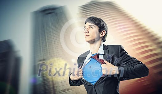 Image of young businessman showing superhero suit underneath his shirt standing against city background Image of young businessman showing superhero suit underneath his shirt standing against city background