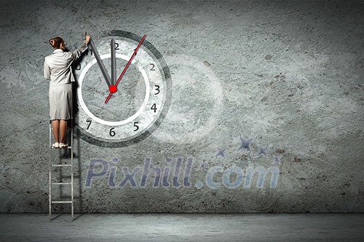 Businesswoman standing on ladder moving hands of clock Businesswoman standing on ladder moving hands of clock