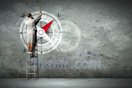 Businesswoman drawing compass with finger on wall standing on ladder Businesswoman drawing compass with finger on wall standing on ladder