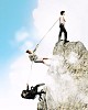 Image of three businesspeople pulling rope atop of mountain