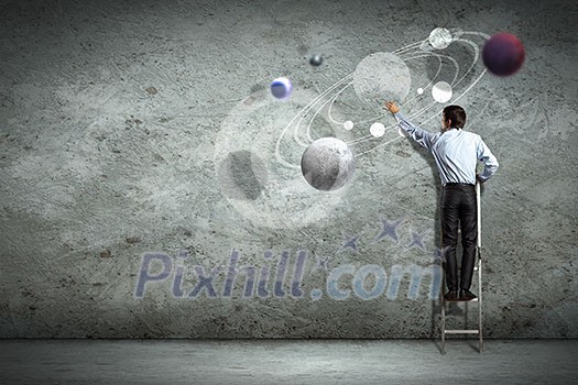 Image of businessman drawing planets on wall Image of businessman drawing planets on wall